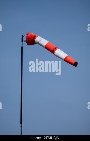 Helsinki / Finnland - 9. MAI 2021: Nahaufnahme von gestreiften Windsocken, die im Wind gegen einen strahlend blauen Himmel waten. Stockfoto