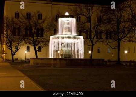 Brunnen am Geschwister-Scholl-Platz, nachts vor der Ludwig-Maximilians-Universität in München. Die Universität gehört zu den ältesten Universitäten Stockfoto