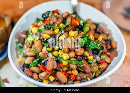 Makro-Nahaufnahme mit Textur aus Bohnensalat mit Koriander, roten Zwiebeln, Rosinen, Paprika und Mais als Abendessen für die Familie mit Bokeh Hintergrund Stockfoto