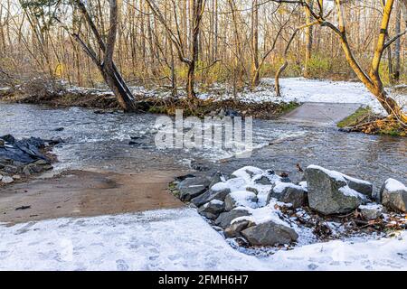 Der Sugarland Run Stream Valley Trail im Norden von Virginia Fairfax County mit Überdachter Weg durch Wasser und Schnee im Winter mit niemand Bei Sonnenuntergang Stockfoto