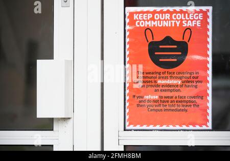 Bedecken Sie Ihr Gesicht mit einem Maskenschild an der Schule Tür Stockfoto