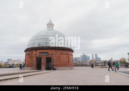 Greenwich, London - 2021.05.08: Der Blick auf den Greenwich Foot Tunnel Eingang mit Canary Wharf im Hintergrund Stockfoto