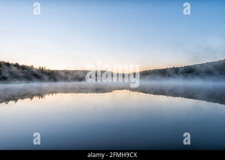 Fichte Knob Lake blaues Wasser in West Virginia bei Sonnenaufgang mit gelbem Sonnenlicht, niemand und Landschaftsansicht von Waldbäumen im Herbst Saison Stockfoto