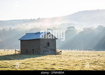 Sonnenaufgang Morgen Silhouette der landwirtschaftlichen verlassenen Ziegel Speicher Scheune Schuppen Im Herbst Landschaft Bauernhof Feld in der ländlichen Landschaft des Westens Virginia mit Stockfoto