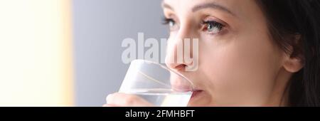 Junge Frau hält Glas in den Händen und trinkt Wasser Von ihm Stockfoto