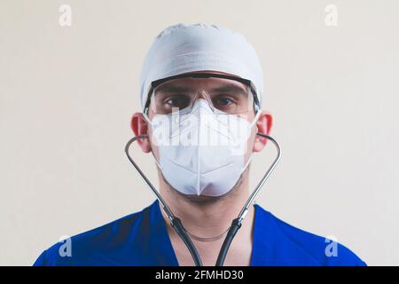 Junger Arzt Porträt in blauen Chirurgen Anzug und schützende Atmung Maske Gläser und Stethoskop auf dem gelben Hintergrund isoliert Stockfoto