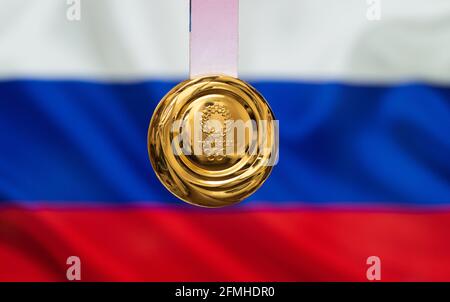 25. April 2021 Tokio, Japan. Goldmedaille der XXXII. Olympischen Sommerspiele 2020 in Tokio auf dem Hintergrund der russischen Flagge. Stockfoto