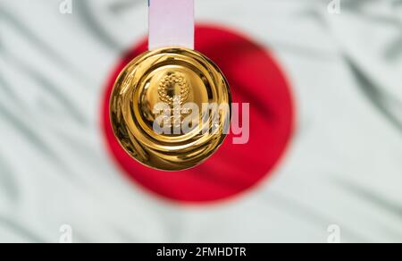 25. April 2021 Tokio, Japan. Goldmedaille der XXXII. Olympischen Sommerspiele 2020 in Tokio auf dem Hintergrund der Flagge Japans. Stockfoto