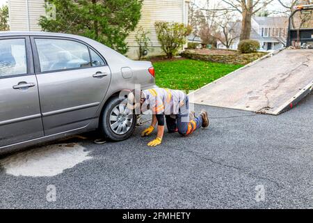 Herndon, USA - 21. November 2020: Geparktes Auto in der Auffahrt mit Turmmann, der eine Kette am Abschleppfahrzeug anschloss, da Kraftstoffleck den Straßenbelag beschädigt hatte Stockfoto