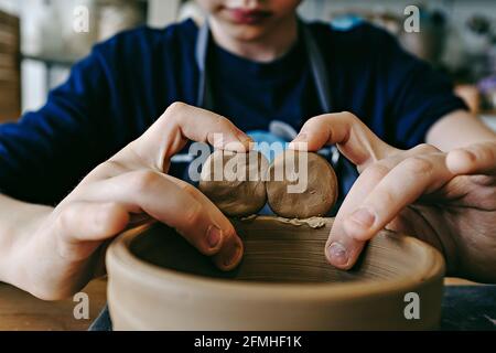 Hände eines jungen Künstlers, der im Kunststudio eine Tonschale modelliert. Traditionelle Töpferkunst. Keramikwerkstatt Konzept Stockfoto