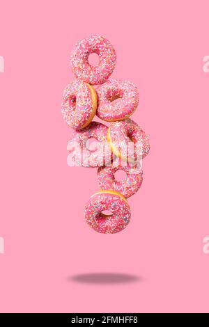 Erstaunliche Donuts auf weichem rosa Hintergrund. Blick von oben auf leckere frische hausgemachte Donuts. Dekoriert mit Konfetti in Form von kleinen Herzen. Levitation. Stockfoto