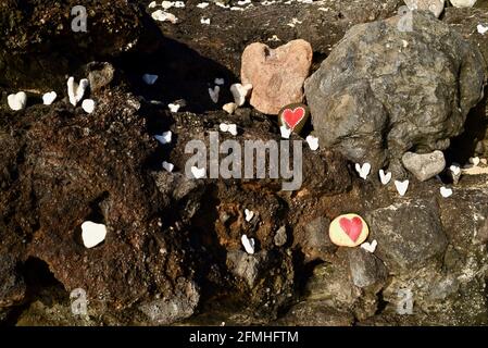 Herzförmige Korallen und Steine, bemalt mit leuchtend roten "Liebesherzen", in vulkanischen Felsen am Ufer des Sandy Beach Park, Oahu, Hawaii, USA platziert Stockfoto