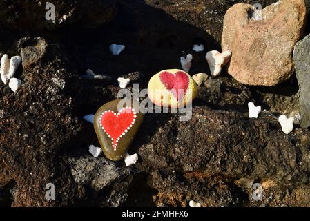 Herzförmige Korallen und Steine, bemalt mit leuchtend roten "Liebesherzen", in vulkanischen Felsen am Ufer des Sandy Beach Park, Oahu, Hawaii, USA platziert Stockfoto