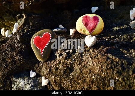 Herzförmige Korallen und Steine, bemalt mit leuchtend roten "Liebesherzen", in vulkanischen Felsen am Ufer des Sandy Beach Park, Oahu, Hawaii, USA platziert Stockfoto