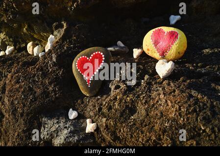 Herzförmige Korallen und Steine, bemalt mit leuchtend roten "Liebesherzen", in vulkanischen Felsen am Ufer des Sandy Beach Park, Oahu, Hawaii, USA platziert Stockfoto