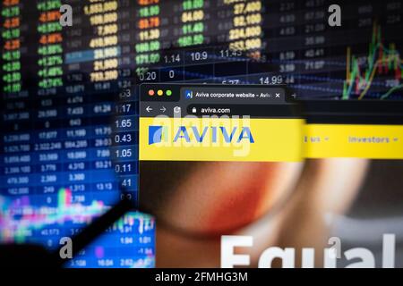 Aviva Firmenlogo auf einer Website mit verschwommenen Börsenentwicklungen im Hintergrund, die auf einem Computerbildschirm durch eine Lupe gesehen werden Stockfoto