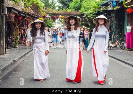 Drei vietnamesische Frauen in konischen Hüten und traditionellen Kleidern von Ao dai, Hoi an, Vietnam Stockfoto