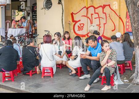 Vietnamesische Familien sitzen auf roten Hockern im Street Food Cafe, Hoi an, Vietnam Stockfoto