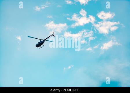 Hubschrauber gegen den Himmel. Ein kleiner Hubschrauber fliegt vorwärts. Eine Aufnahme eines Hubschraubers in Bewegung mit nur zwei Klingen. Stockfoto