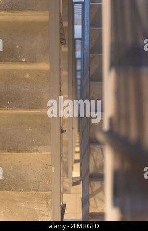 Eine Treppe in einem Hochhaus. Die Treppen gehen tief nach unten. Betontreppen durch alle Etagen. Stockfoto