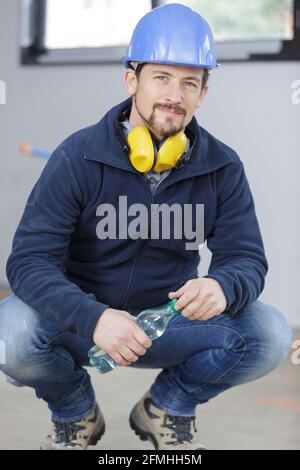 der baumeister sitzt in einem Helm auf den Knien Stockfoto