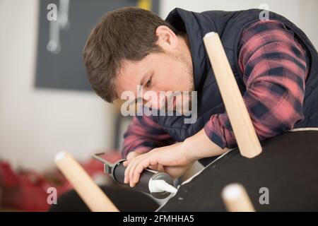 Ehefrau hilft Ehemann, kaputten Stuhl zu Hause zu reparieren Stockfoto