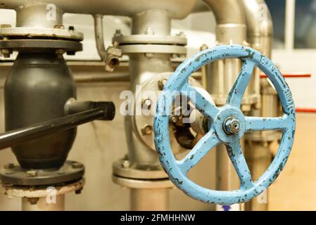 Großes Ventil am Rohr. Großes altes blaues Ventil am Rohr. Englische Inschriften auf der alten Klappe. Stockfoto