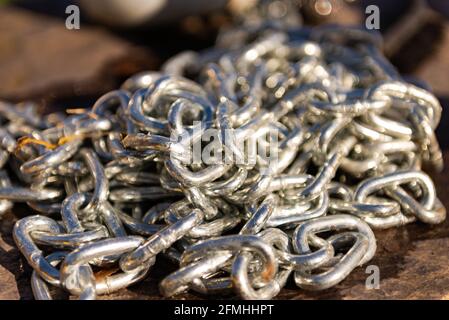 Eine Reihe von Chrom-Kette. Eine dicke Metallkette liegt in einem großen Haufen auf dem Stein. Sehr Nahaufnahme der Kette. Stockfoto