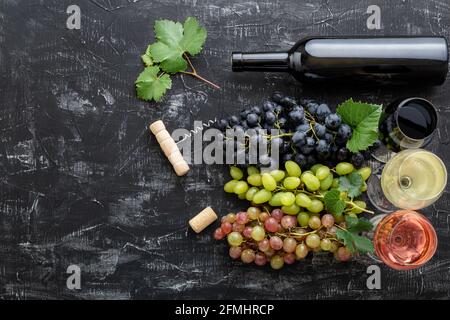 Sortiment verschiedene Arten von Wein und Sorten. Verkostung von weißem Rosé-Rotwein in Gläsern in der Nähe von weißen rosa und schwarzen Trauben, Rotwein-Flasche auf Stockfoto