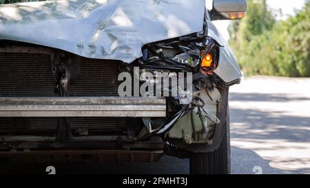 Zerstörtes Auto im Autounfall Verkehrsunfall auf der Stadtstraße auf der Stadtstraße. Zertrümmerte defekte vordere Auto-Scheinwerfer, verbeulte Haube ohne Stoßstange bei Autounfall Stockfoto