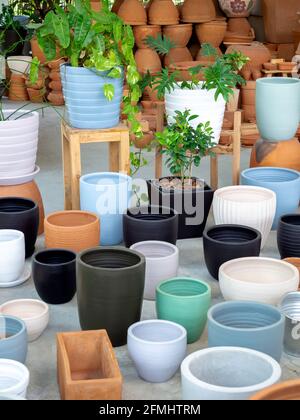 Verschiedene bunte Keramik- und Terrakotta-Pflanzentöpfe auf Betonboden angeordnet. Leere geometrische Keramik Blumentopf Hintergrund, vertikalen Stil. Stockfoto