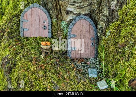 Kleine Türen und Pilze in einem Korb aus Fimo auf einem Baum wie ein Märchenhaus aus nächster Nähe Stockfoto