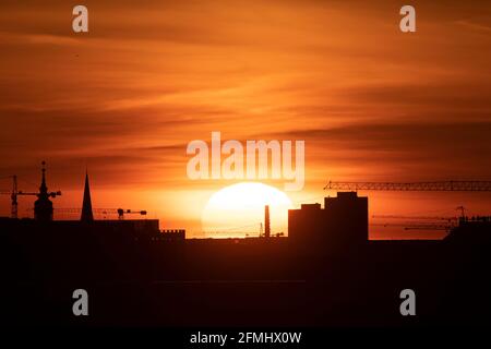 Berlin, Deutschland. Mai 2021. Die Sonne geht in der Berliner Skyline zwischen mehreren Baukräne auf. Quelle: Fabian Sommer/dpa/Alamy Live News Stockfoto