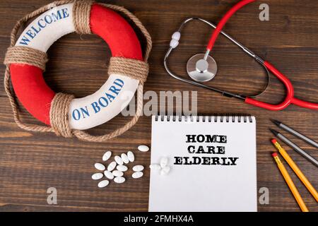 Altenpflege. Notieren Sie Papier, Stethoskop und Büromaterial auf einem Holztisch. Stockfoto