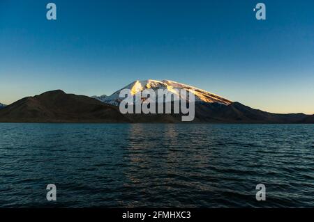Sonnenuntergang am See Karakul mit Muztagata Berg im Hintergrund, Provinz Xinjiang, China Stockfoto