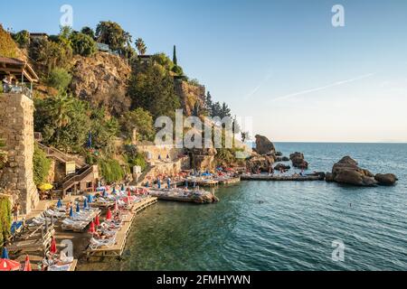 Nicht identifizierte Menschen sonnen sich am kleinen Strand in der Kaleici Altstadt von Antalya. Stockfoto