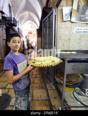 Ein palästinensischer Junge, der ein Tablett mit Atayef hält - EIN traditionelles Dessert, das während des heiligen Monats Ramadan und besonders während der Eid Al Fitr-Feiertage beliebt ist. Stockfoto