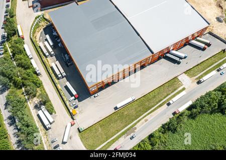 Lastkraftwagen im Industrielager oder Logistikzentrum warten auf das Verladen von Waren. Luftaufnahmen mit Drohne Stockfoto