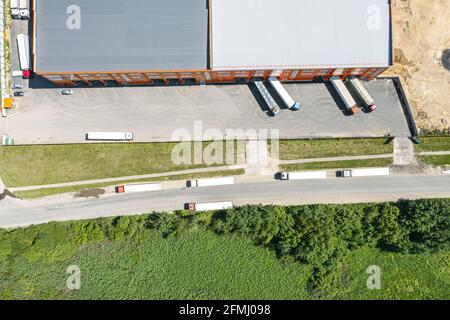 Frachtrailer entladen Waren im Logistikzentrum. Luftaufnahme von oben Stockfoto