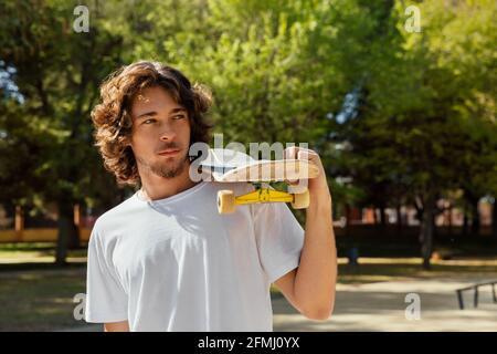 Porträt eines Skateboarders, der sein Board über eine Schulter hält. Stockfoto