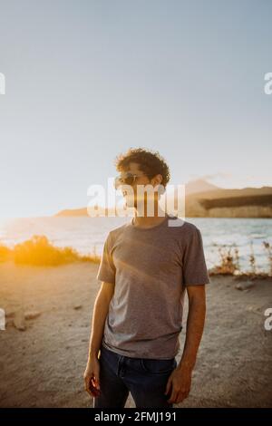 Seitenansicht männliche Reisende in legerer Kleidung und Sonnenbrillen klatschen Genießen Sie die sandige Küste bei einem malerischen Sonnenuntergang, während Sie den Sommer verbringen Urlaub in Fyri Stockfoto