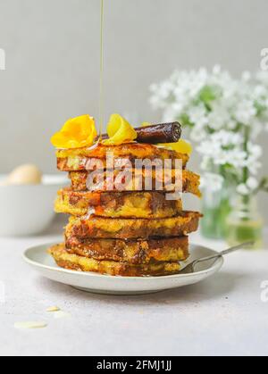 Ein Haufen süßer französischer Toasts, die mit Honig gegossen wurden, serviert Auf dem Teller zum Frühstück in der Küche Stockfoto