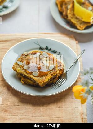 Von oben von schmackhaftem French Toast, der mit Honig gegossen wurde Und garniert mit Mandelflocken serviert auf dem Teller auf dem Tisch Zum Frühstück Stockfoto