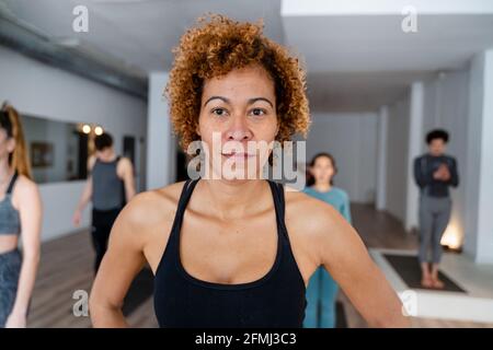 Inhalt weiblich mit Afro-Frisur im geräumigen Studio mit stehen Verschiedene Menschen während des Yoga-Kurses Stockfoto