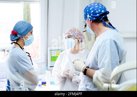 Anonymer Chirurg im medizinischen Fernglas im Gespräch mit weiblichen Kollegen In sterilen Masken, während man sich im Krankenhaus ansieht Stockfoto