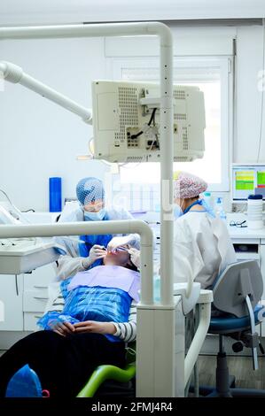Anonymer Zahnarzt mit Kollegen in Uniformen, die Zähne des Patienten operieren Einsatz von medizinischen Werkzeugen in modernen Kliniken Stockfoto