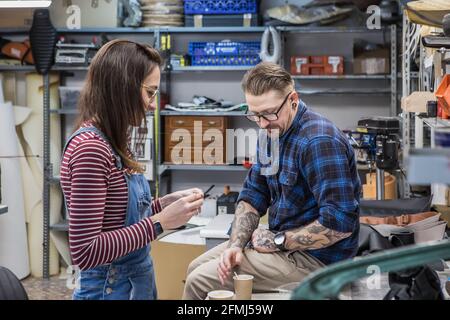 Seitenansicht von ein paar Kunsthandwerkern, die während der Kaffeepause eine Kaffeepause einlegen Arbeiten Sie in einer kreativen Werkstatt Stockfoto