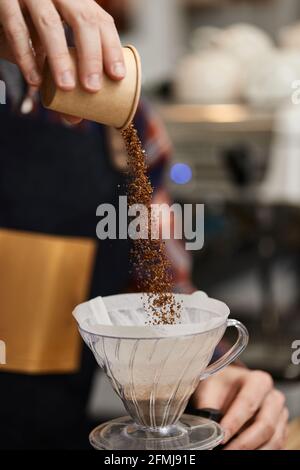 Männliche Hände gießen gemahlenen Kaffee in den Filter. Stockfoto