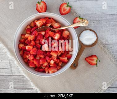 Eine Schüssel mit frisch gehackten Erdbeeren und Xilitolzucker auf beigem Hintergrund. Ansicht von oben Stockfoto