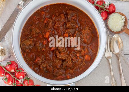 Köstliches Rinderragout in einem weißen Eintopf serviert Holztisch Hintergrund Stockfoto